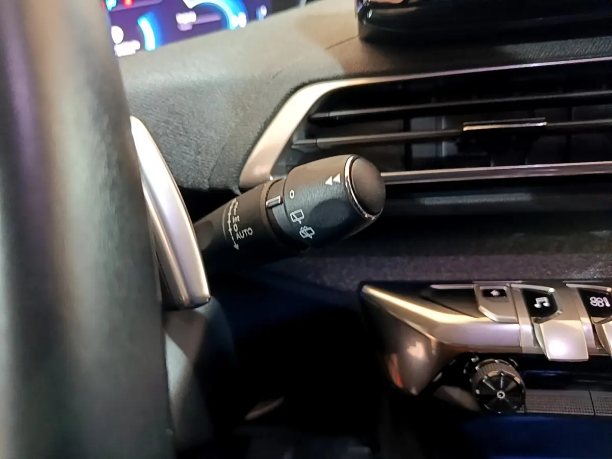 Gros plan sur la commande d’essuie-glace à gauche du volant dans l’habitacle bleu du Peugeot 3008 hybride rechargeable 2021.
