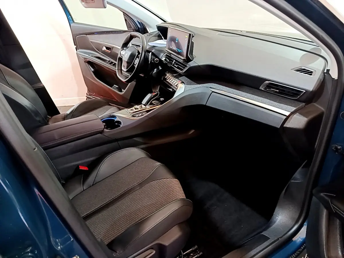 Intérieur du Peugeot 3008 bleu vu côté passager, tableau de bord moderne avec écran tactile et sièges noirs cuir et tissu.