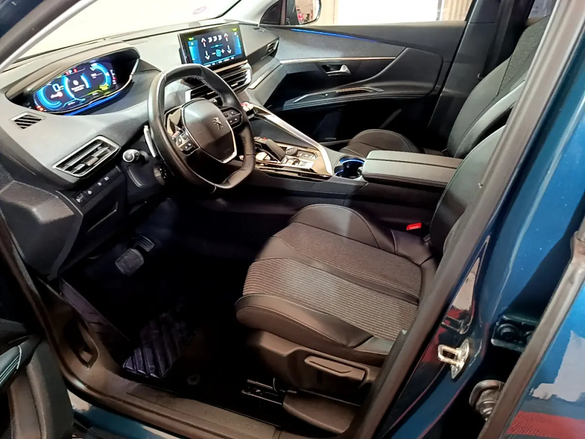 Intérieur côté conducteur bleu Peugeot 3008 Hybrid 2021, volant cuir, tableau de bord digital et sièges noirs.