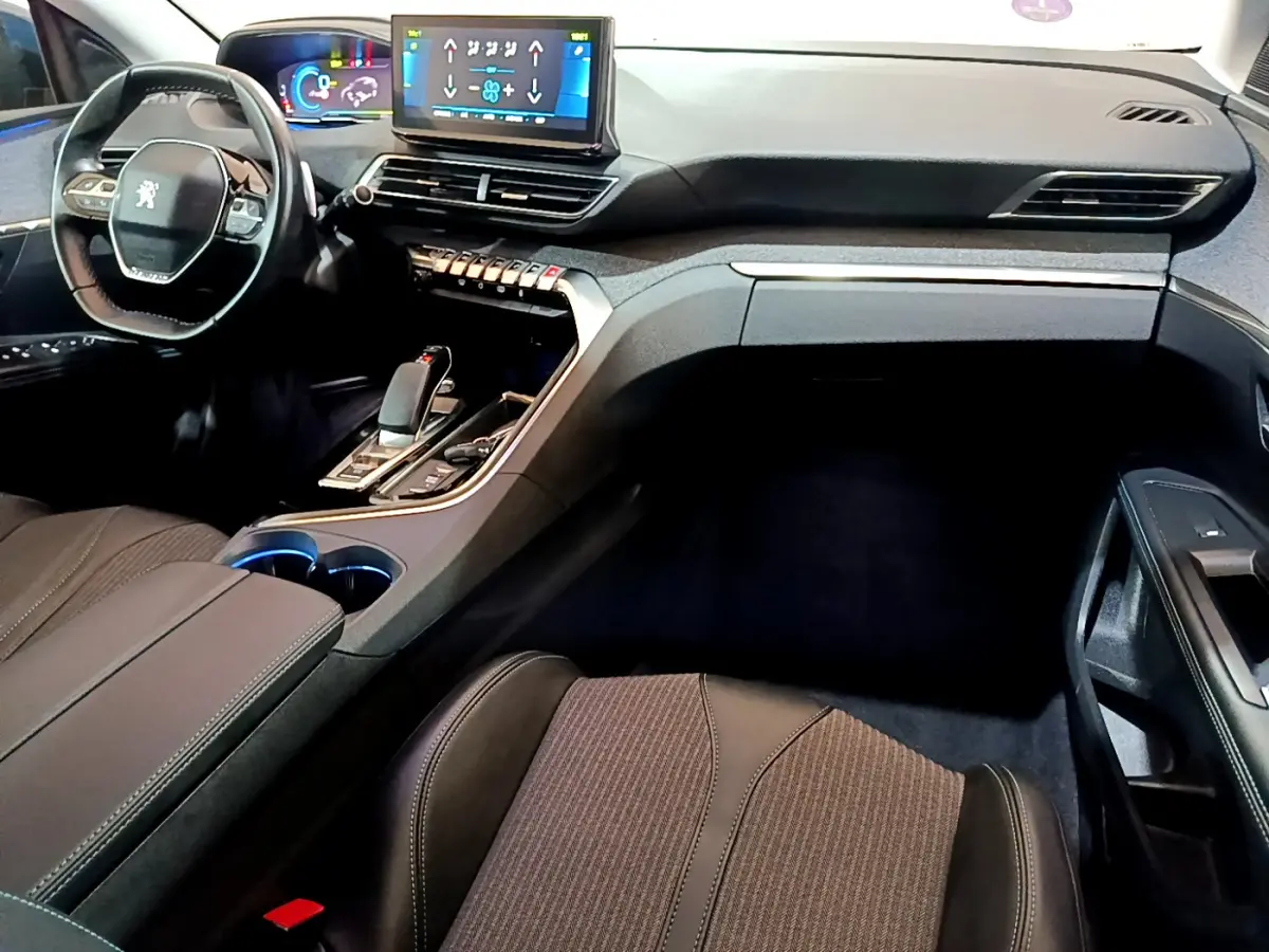 Intérieur du Peugeot 3008 hybride 2021 vu côté passager, tableau de bord moderne avec écran tactile et volant compact.