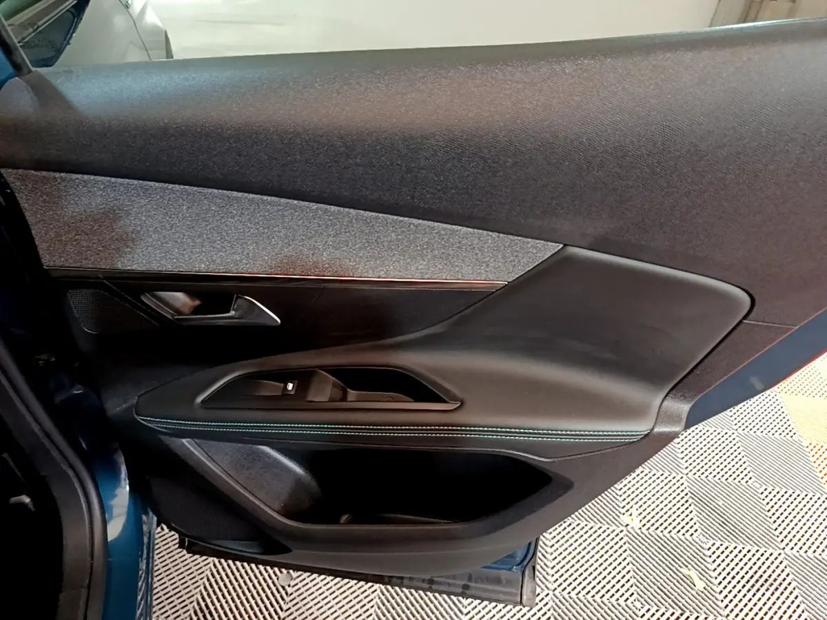 Vue côté gauche de la porte intérieure noire avec surpiqûres bleues du Peugeot 3008 hybride bleu 2021.