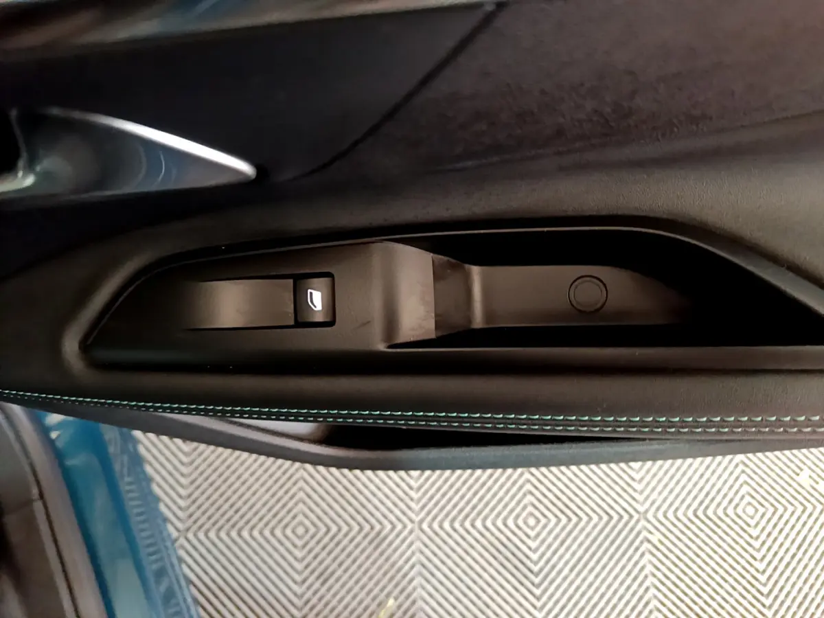Poignée intérieure côté gauche avec bouton de lève-vitre sur porte bleu métallisé d’un Peugeot 3008 hybride 2021