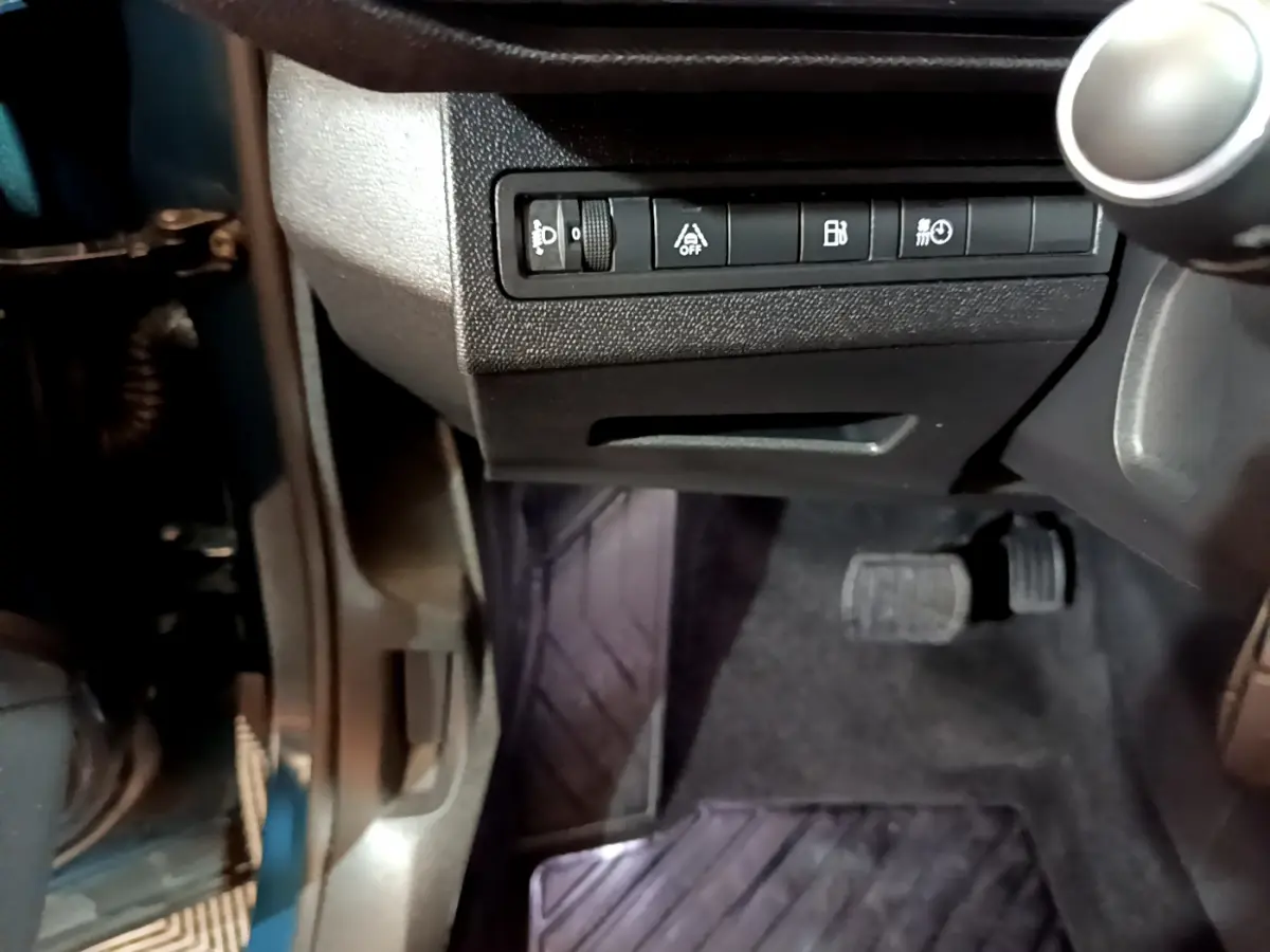 Vue rapprochée côté gauche sous le tableau de bord du Peugeot 3008 bleu, avec pédales et commandes visibles.