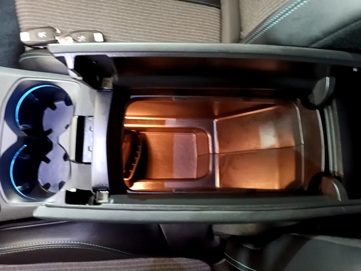 Vue plongeante sur le rangement central éclairé et les porte-gobelets bleutés du Peugeot 3008 hybride rechargeable 2021.