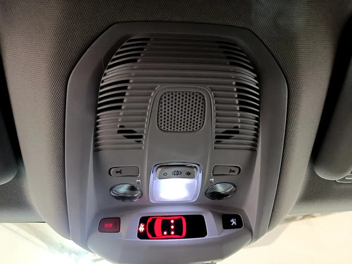 Vue intérieure du plafonnier gris clair du Peugeot 3008 hybride avec boutons SOS et éclairage central allumé.
