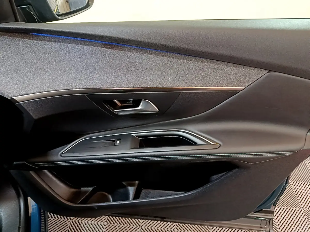 Vue côté gauche de la porte intérieure noire du Peugeot 3008 bleu, avec poignée et bandeau décoratif argenté.