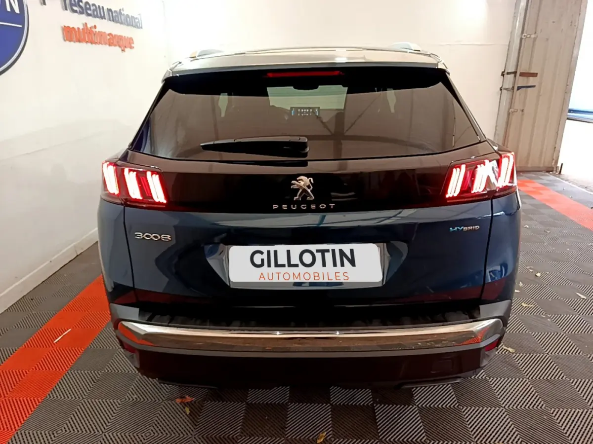 Vue arrière d'un Peugeot 3008 bleu hybride rechargeable avec feux LED allumés dans un garage.