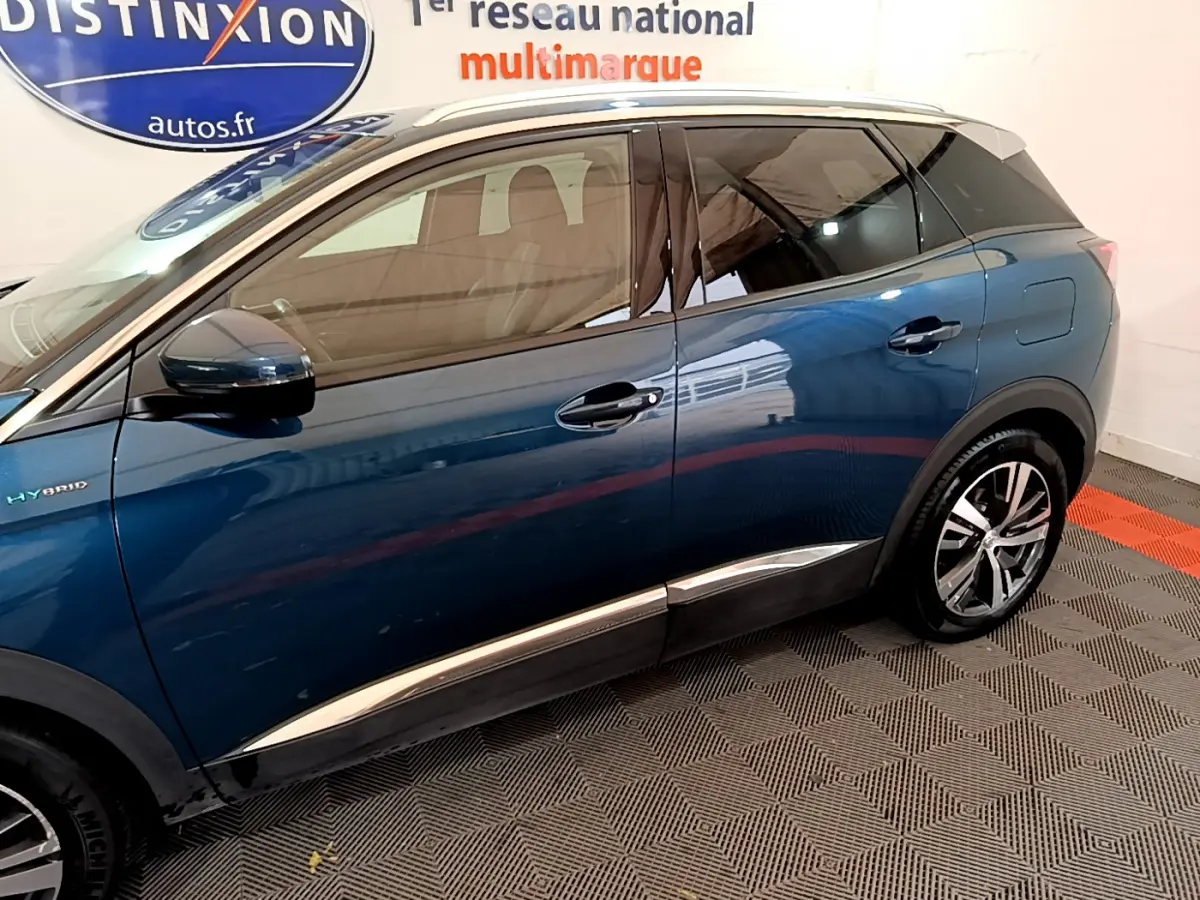Profil côté gauche du Peugeot 3008 hybride rechargeable bleu avec jantes alliage et vitres teintées en intérieur showroom.