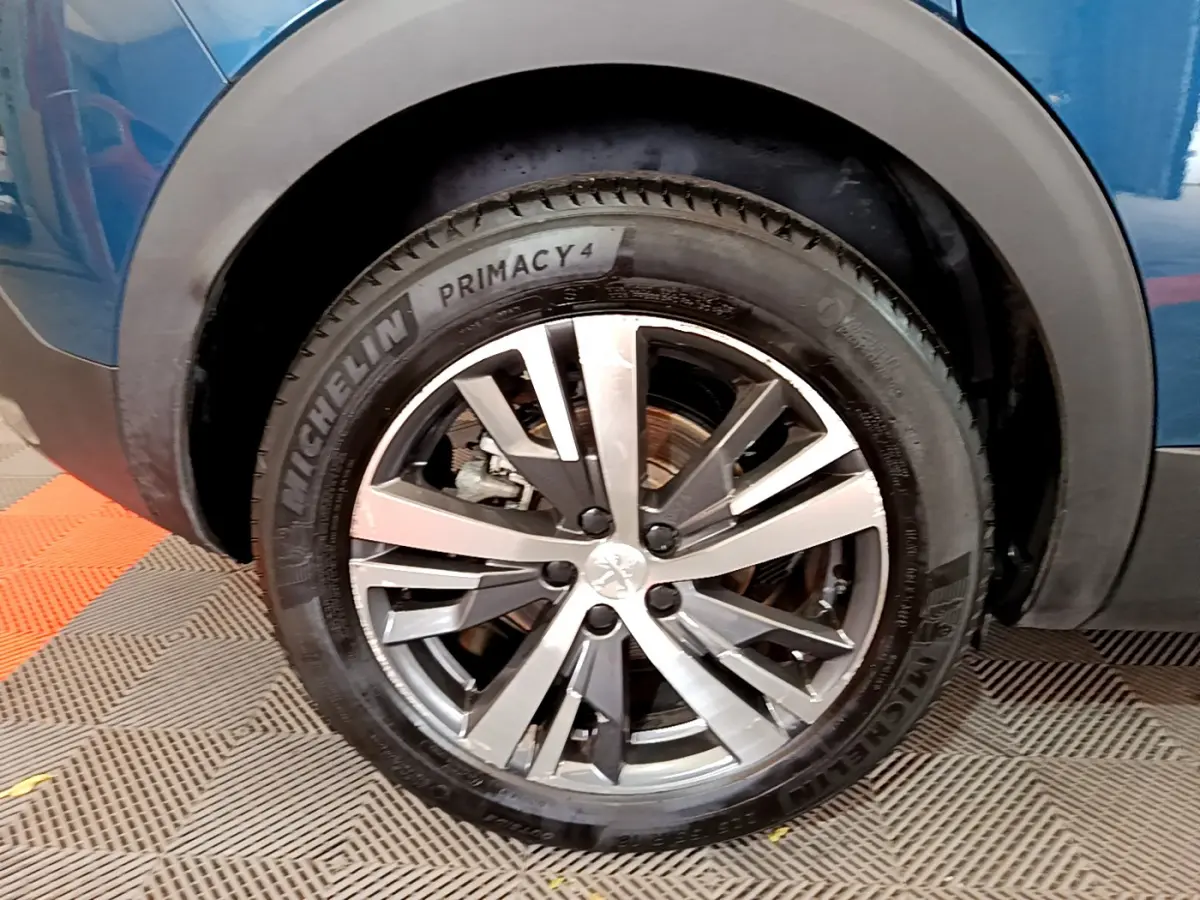 Gros plan sur la roue avant gauche d’un Peugeot 3008 bleu, avec jante alliage et pneu Michelin Primacy 4.