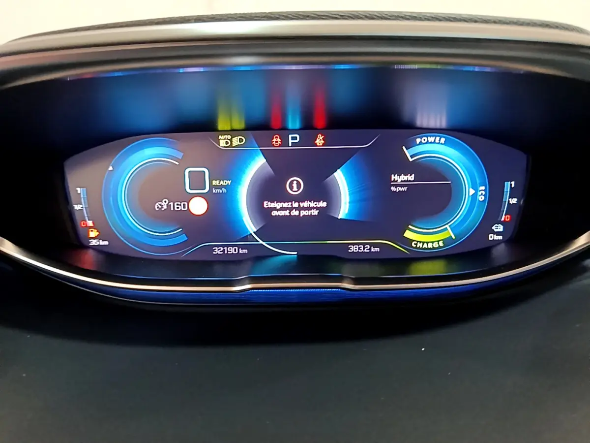 Tableau de bord numérique bleu du Peugeot 3008 hybride, affichant vitesse, autonomie et mode de charge.