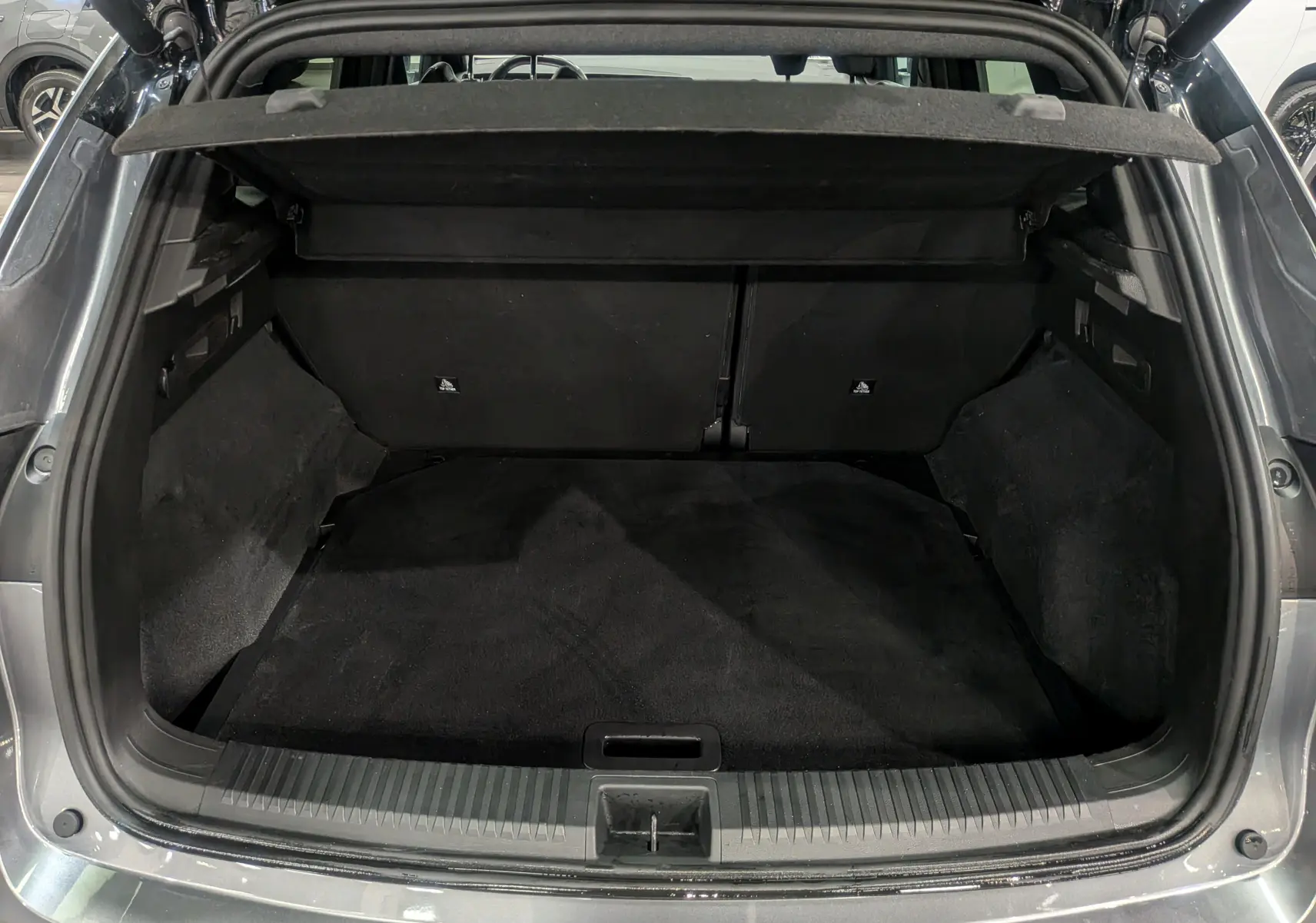 Coffre ouvert d'un Renault Austral gris schiste, vue arrière montrant l'espace de chargement noir et les finitions intérieures.