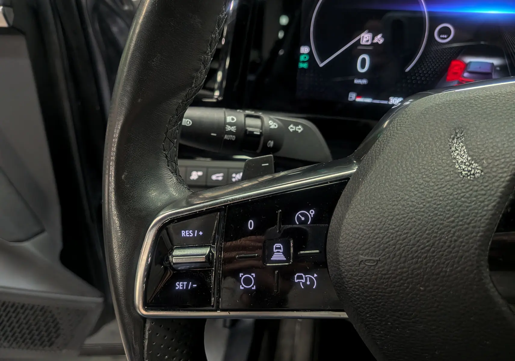 Gros plan sur les commandes du volant noir du Renault Austral 2024, avec affichage digital en arrière-plan.