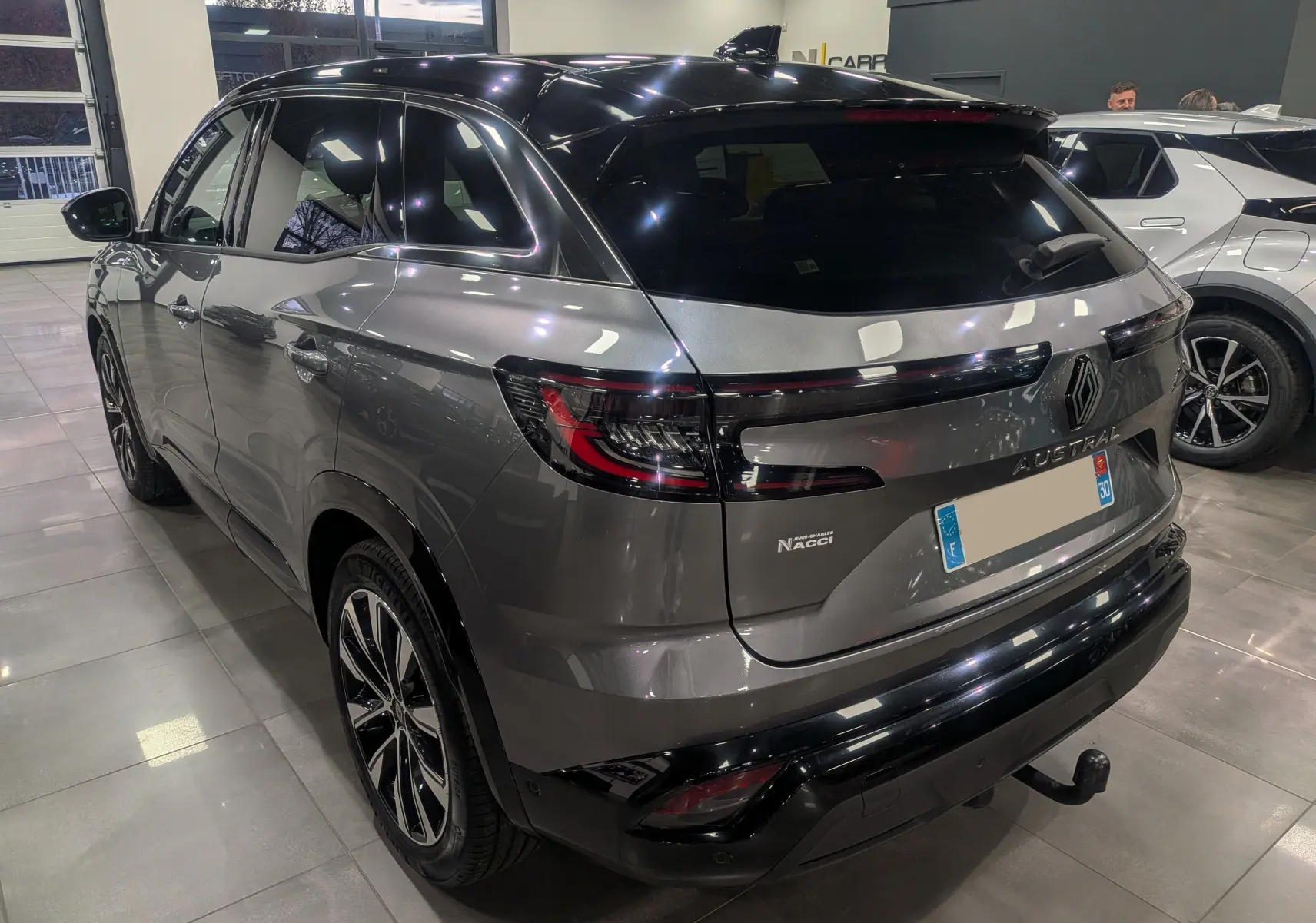 Vue 3/4 arrière droite du Renault Austral gris schiste avec toit noir et jantes biton dans un showroom.