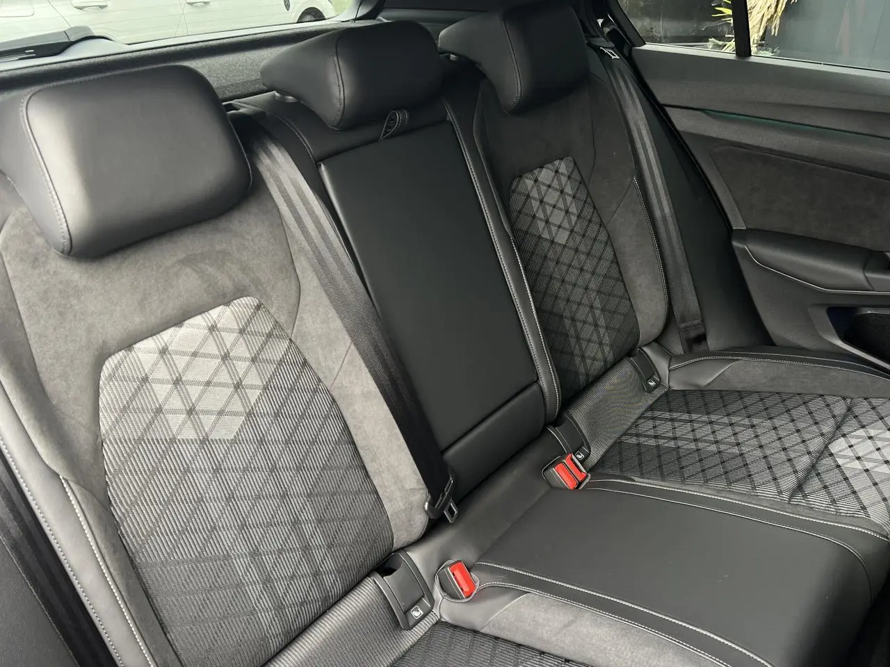 Vue intérieure des sièges arrière en cuir et tissu gris à motifs de la Volkswagen Golf VIII R-Line noire.