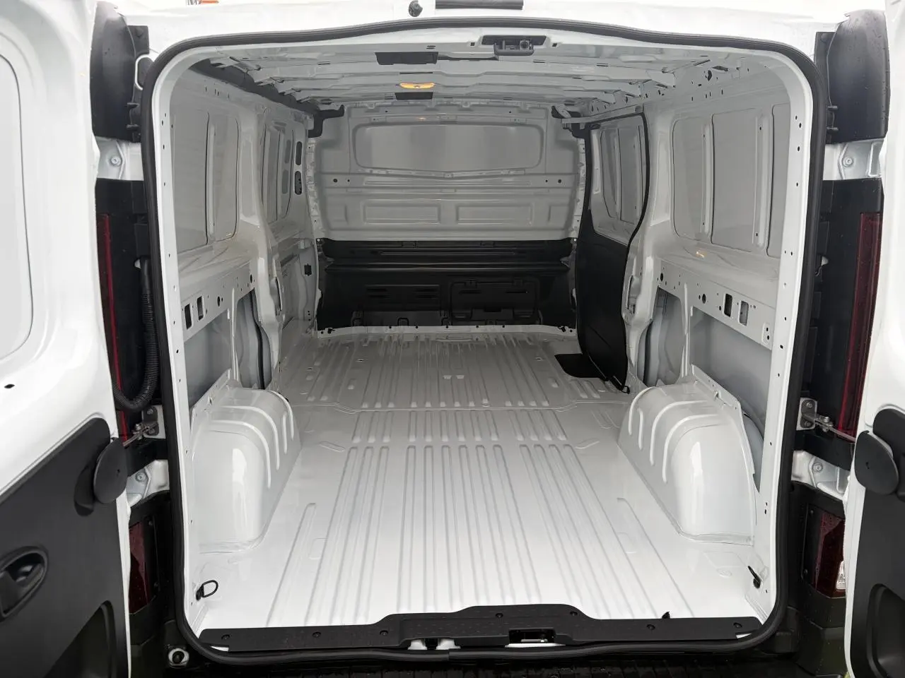 Vue intérieure arrière du Renault Trafic Fourgon blanc glacier, montrant l'espace de chargement vide et tôlé.