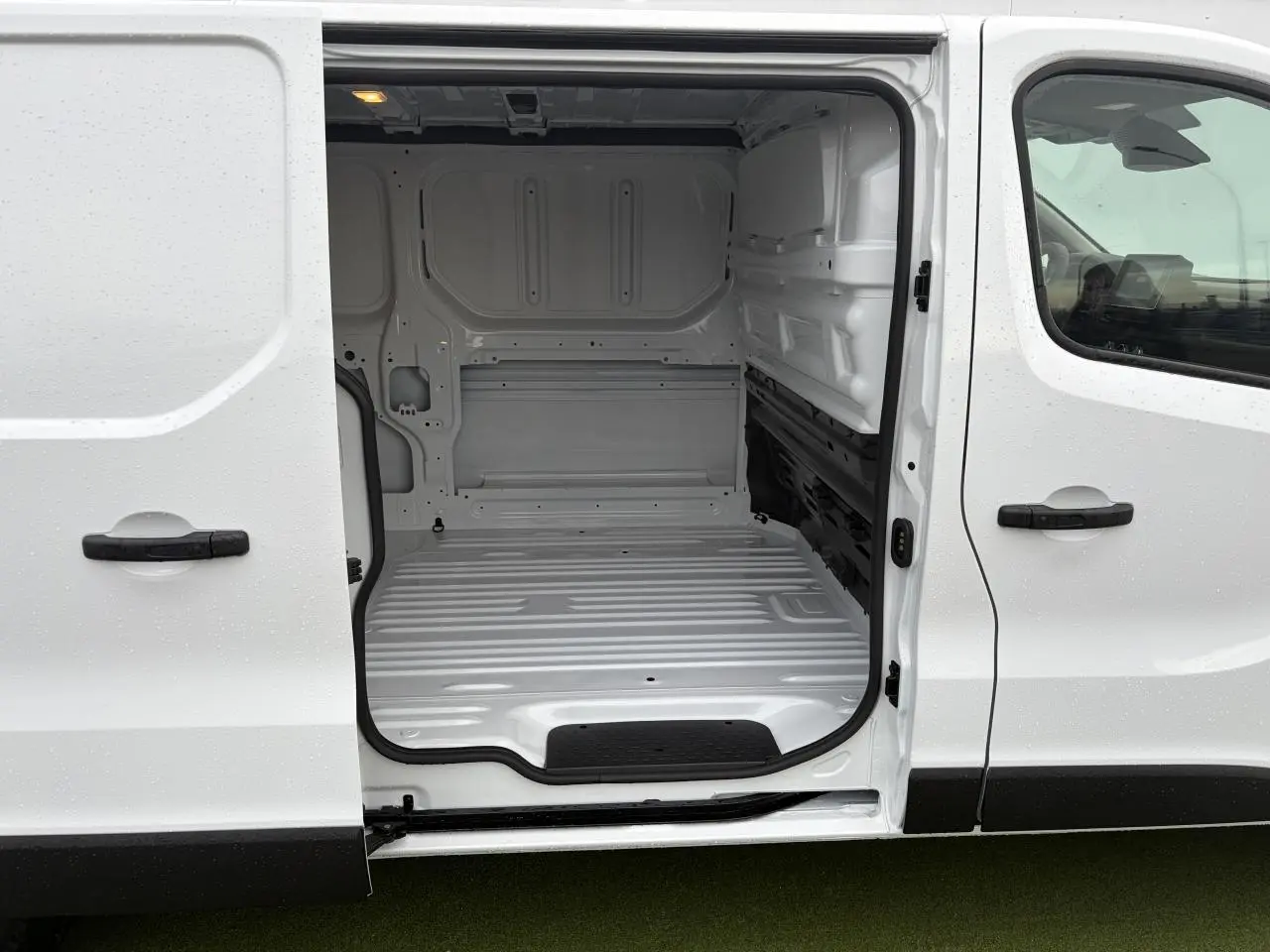 Vue latérale droite sur l’espace de chargement blanc glacier ouvert du Renault Trafic Fourgon 2025, intérieur tôlé vide.