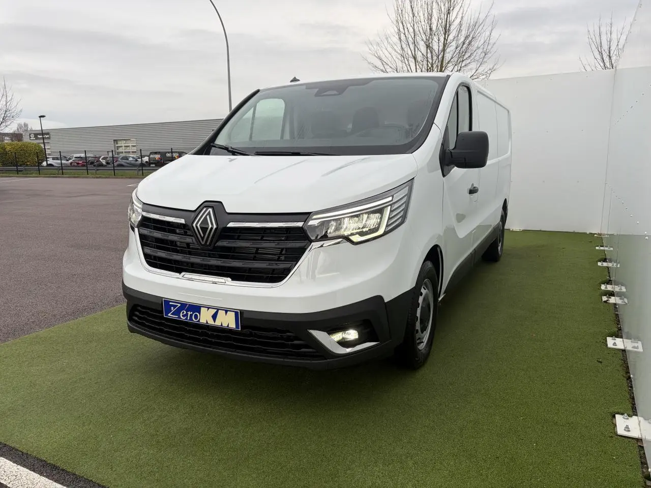 Renault Trafic Fourgon blanc glacier vu en 3/4 avant droit, avec projecteurs LED et calandre noire brillante.