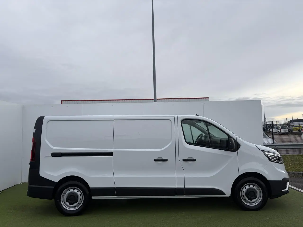 Renault Trafic Fourgon blanc glacier vu de profil côté gauche, avec porte latérale coulissante et jantes tôles 16 pouces.