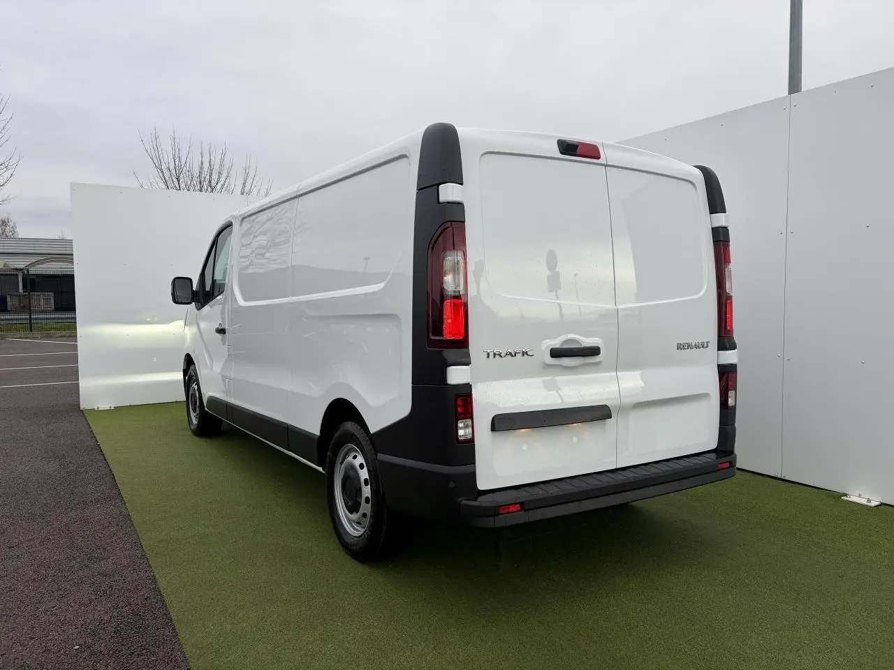 Vue 3/4 arrière droite du Renault Trafic Fourgon blanc glacier avec portes arrière tôlées et jantes tôles 16 pouces.