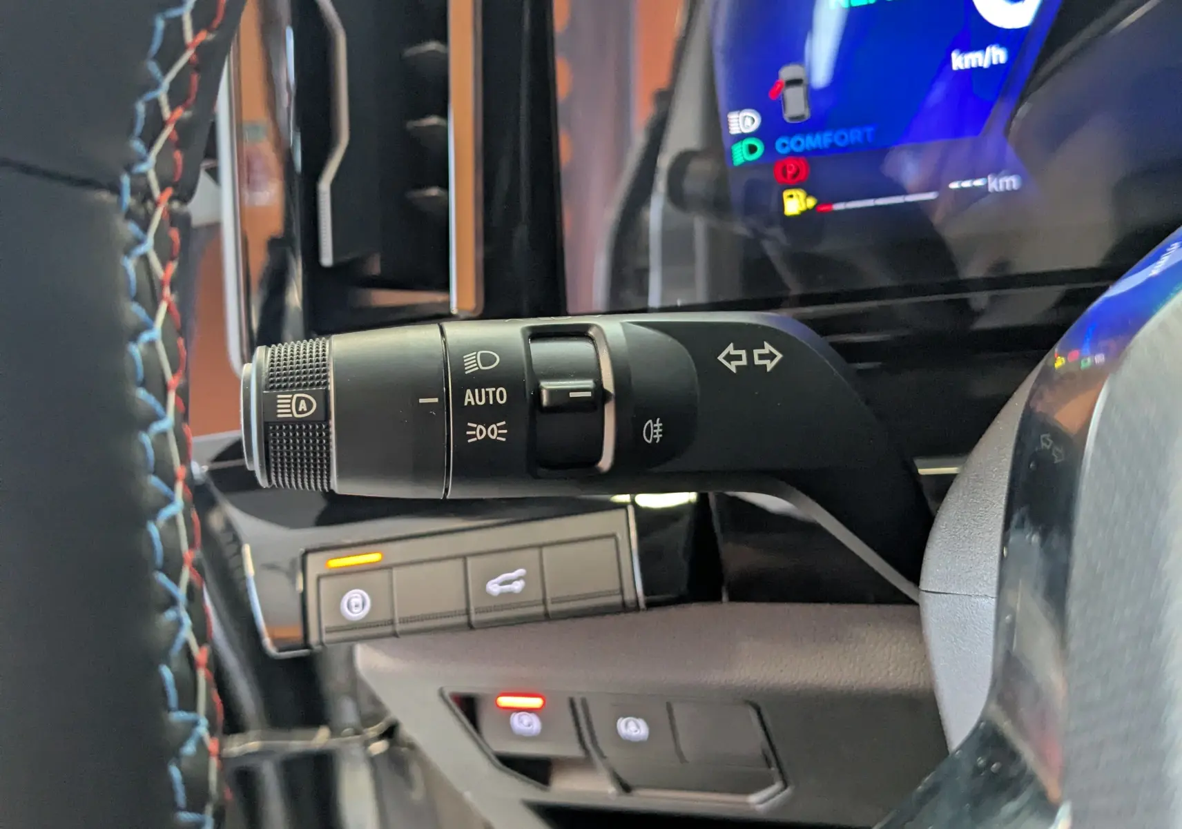 Gros plan sur la commande des feux et clignotants à gauche du volant du Renault Austral gris schiste, tableau de bord numérique visible.
