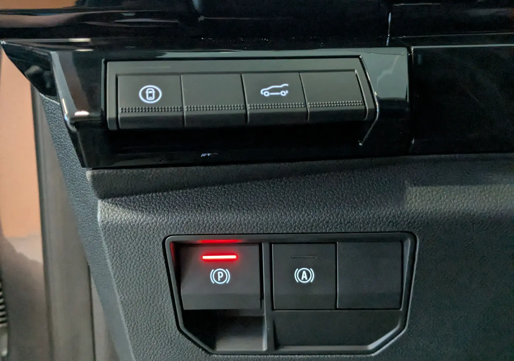 Gros plan sur les boutons de commande du frein de parking et ouverture du coffre, intérieur noir du Renault Austral.