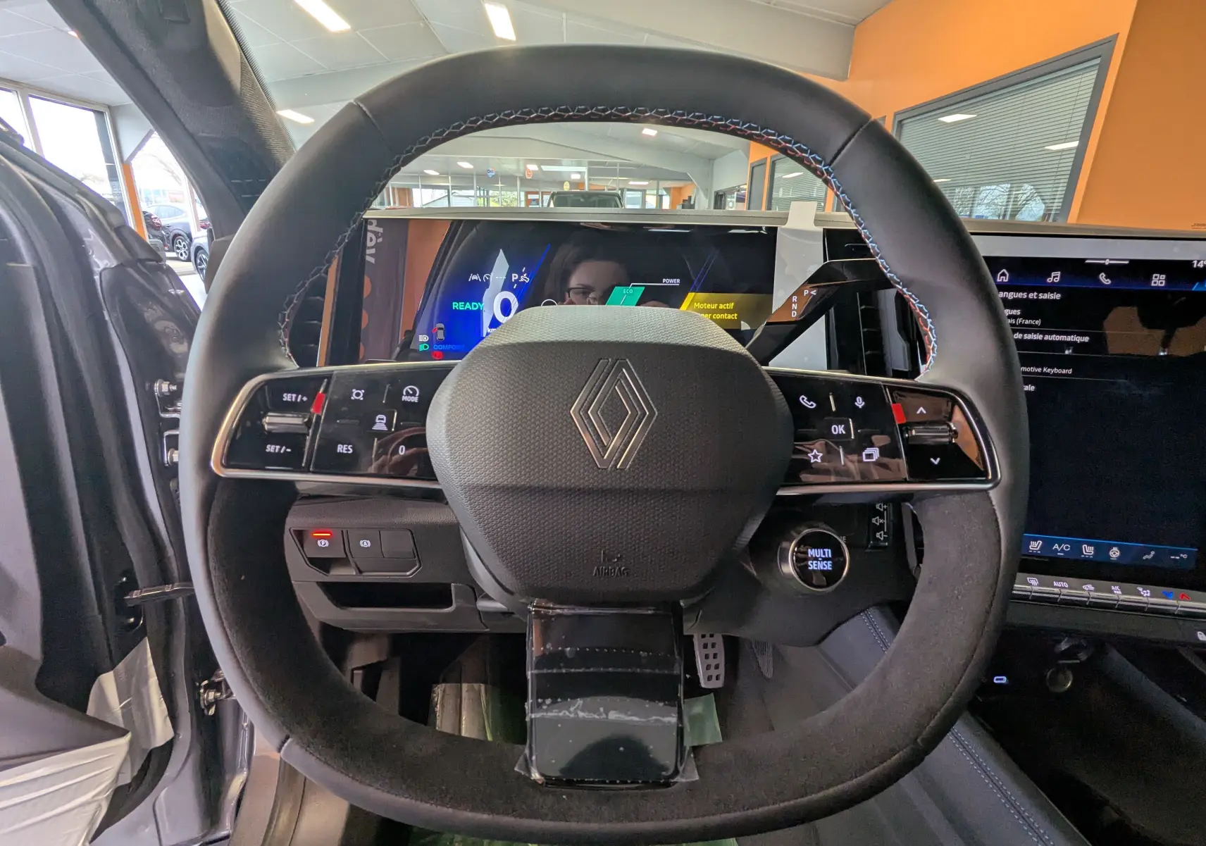 Vue rapprochée du volant noir avec surpiqûres tricolores du Renault Austral E-Tech 200, tableau de bord numérique en arrière-plan.