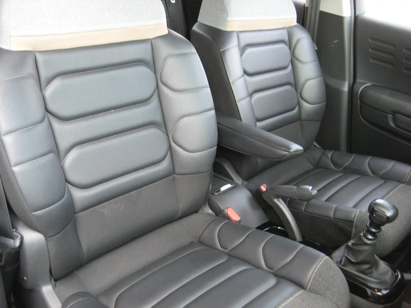 Vue rapprochée des sièges avant en cuir noir du Citroën C3 Aircross gris platinium, avec levier de vitesse manuel visible.