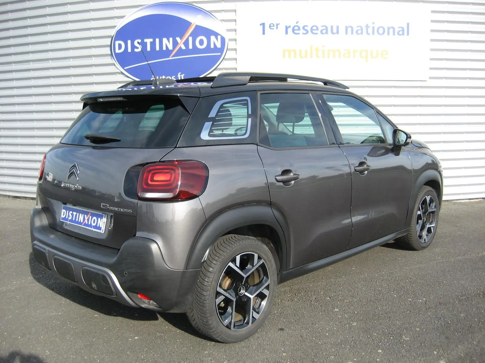 Vue 3/4 arrière droite d'un Citroën C3 Aircross gris platinium avec jantes noires et toit noir.