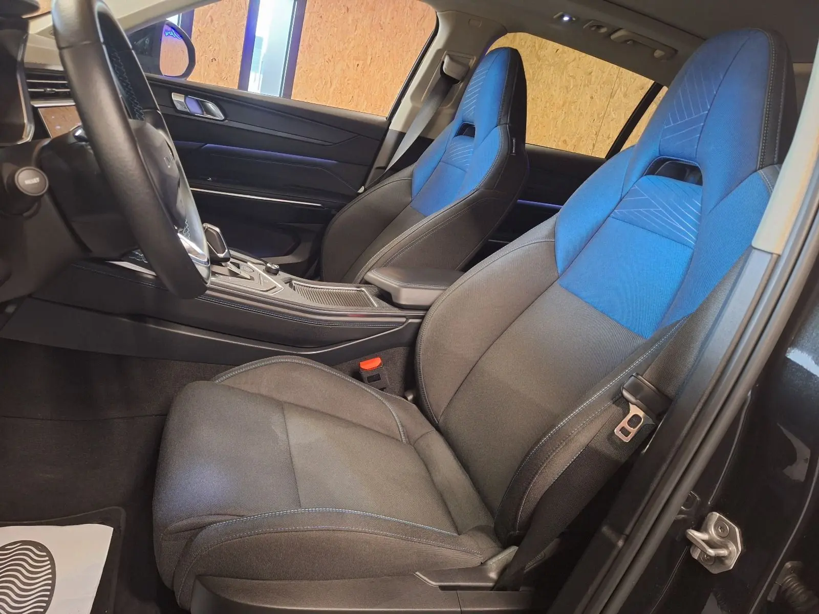 Vue intérieure côté conducteur du Lynk & Co 01 2023, sièges tissu noir et bleu avec console centrale moderne.