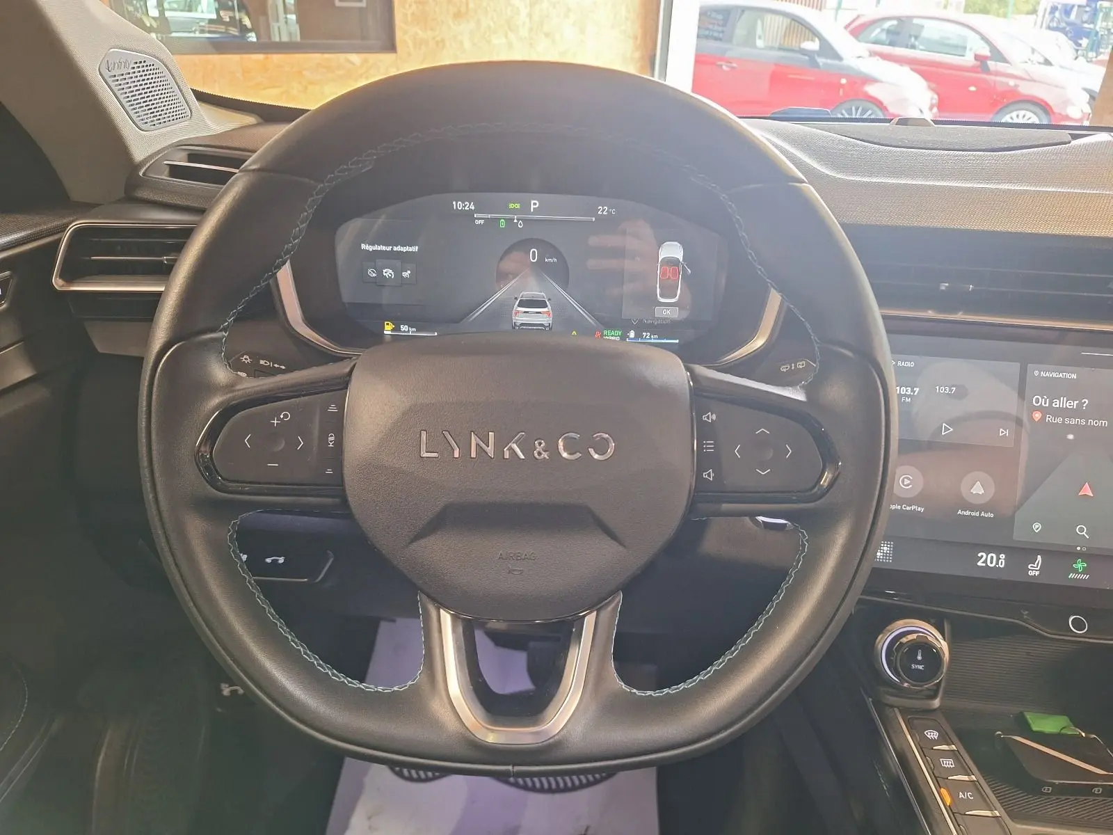 Volant noir de LYNK & CO 01 2023 avec logo central, tableau de bord numérique et écran tactile de navigation visible.