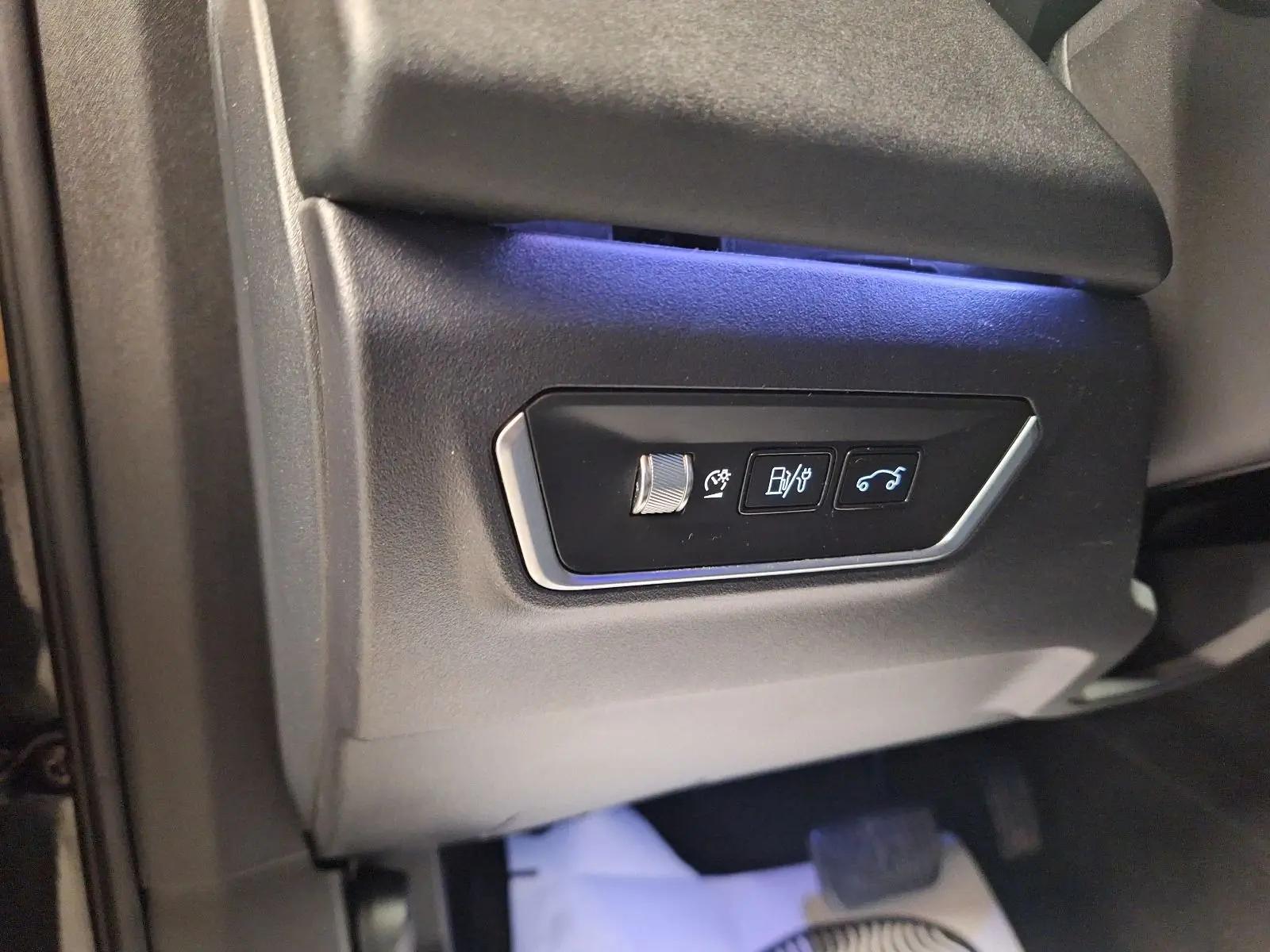 Détail des commandes sous le tableau de bord côté conducteur du Lynk & Co 01 noir avec éclairage bleu.