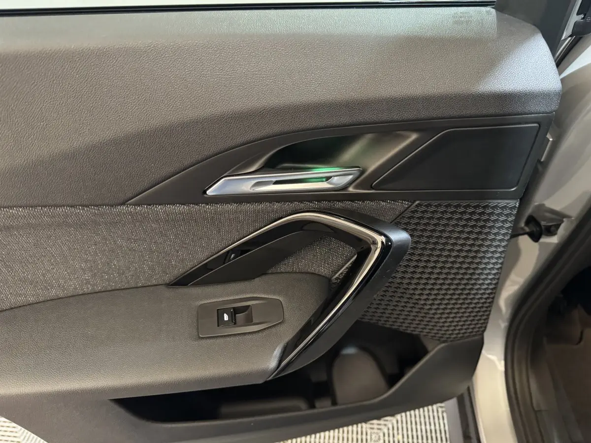 Vue rapprochée de la porte avant droite du BMW X1 2024 gris foncé, avec poignée chromée et habillage texturé.