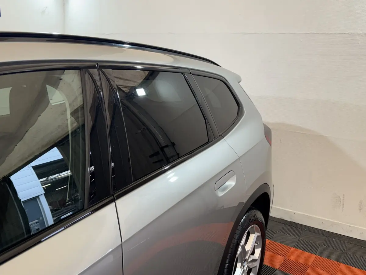 Vue côté arrière droit du BMW X1 sDrive20i gris foncé, mettant en valeur la porte arrière et la jante alliage.