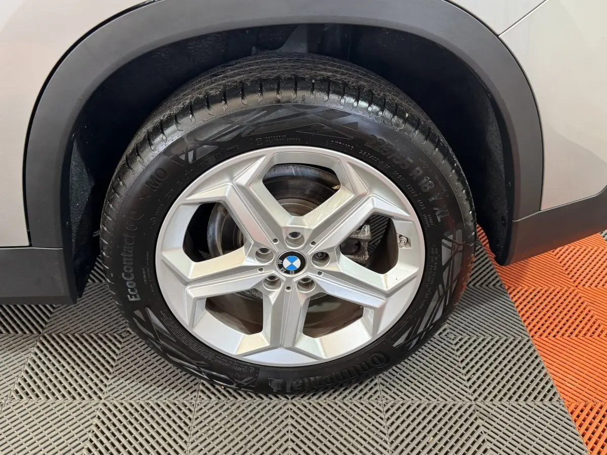 Gros plan sur la roue avant droite avec jante argentée du BMW X1 gris foncé 2024 sDrive20i Business Design.