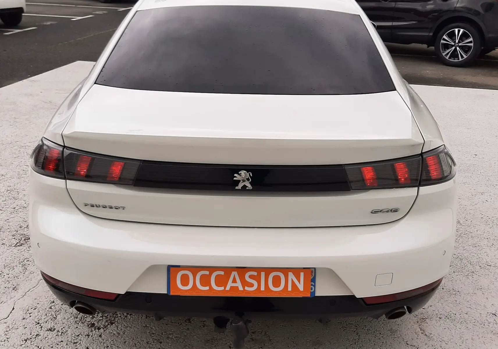 Vue arrière d'une Peugeot 508 blanche de 2019 avec feux LED et plaque "OCCASION" visible sur un parking.