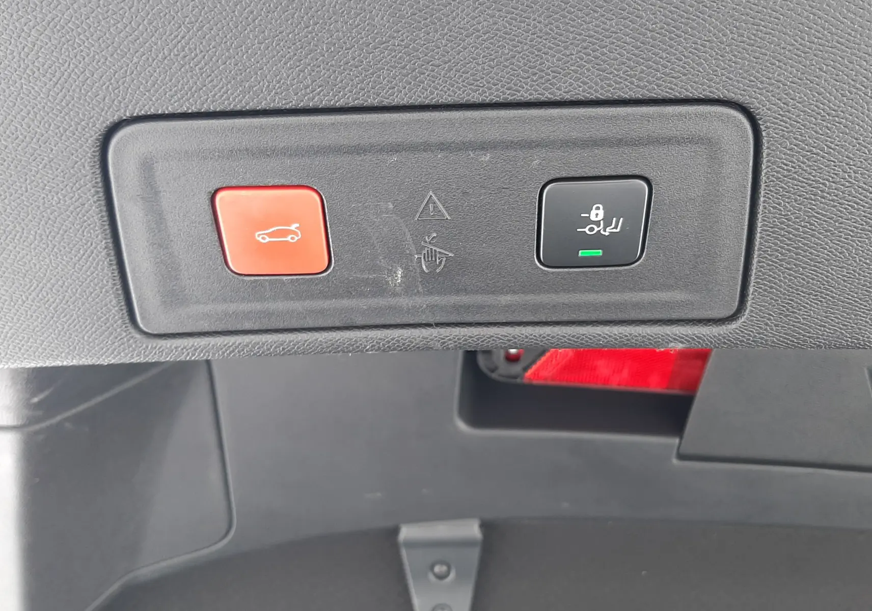 Gros plan sur les boutons de commande du coffre et de la fermeture automatique dans le coffre d'une Peugeot 508 blanche.