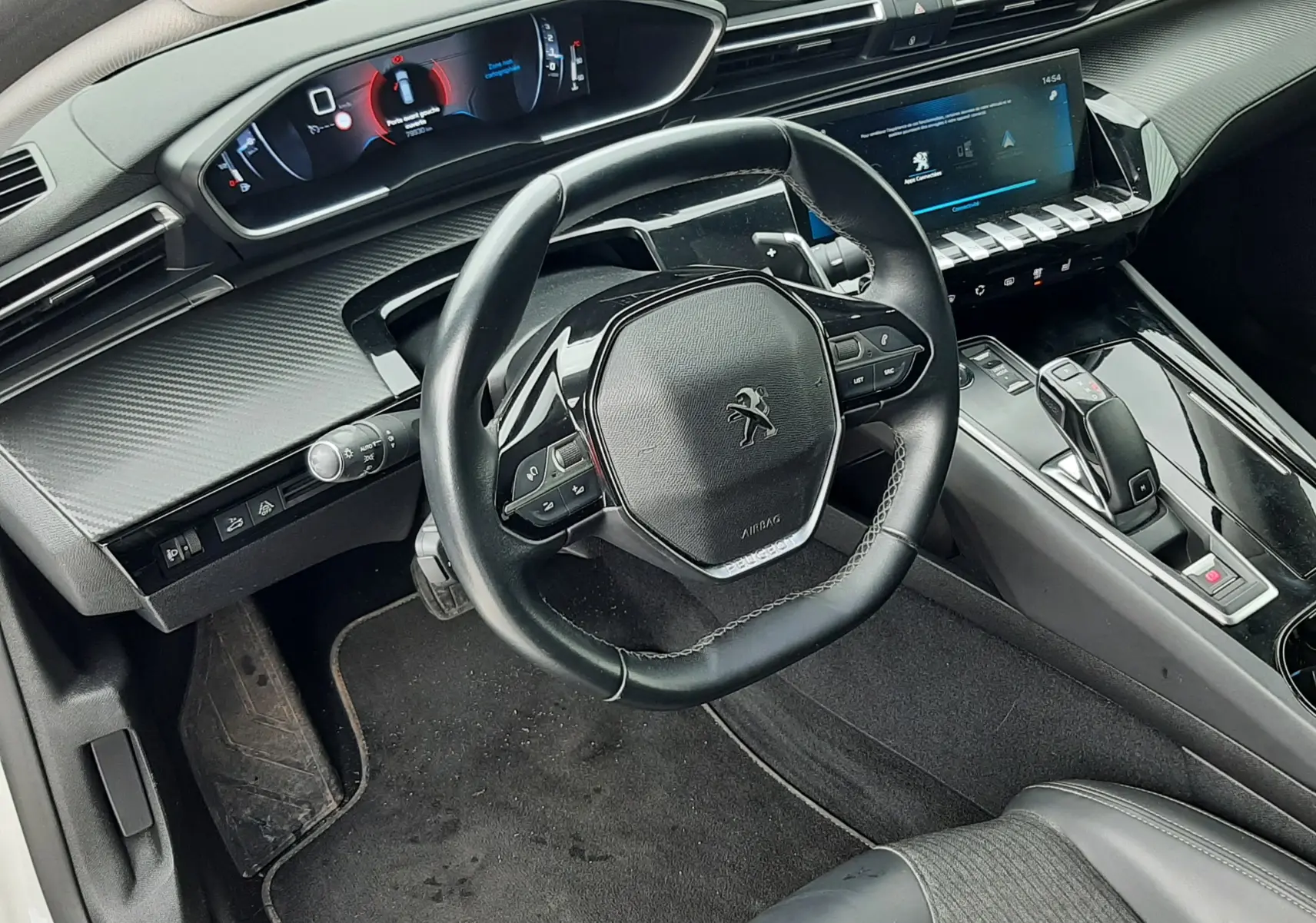 Vue intérieure côté conducteur de la Peugeot 508 blanche, avec volant compact et tableau de bord numérique moderne.