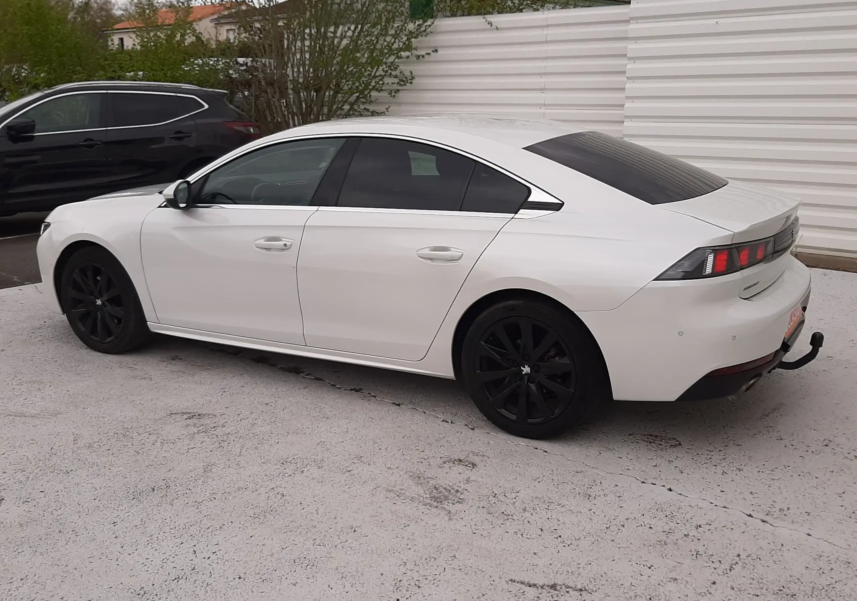 Vue latérale droite d'une Peugeot 508 blanche de 2019 avec jantes noires et attelage arrière visible.