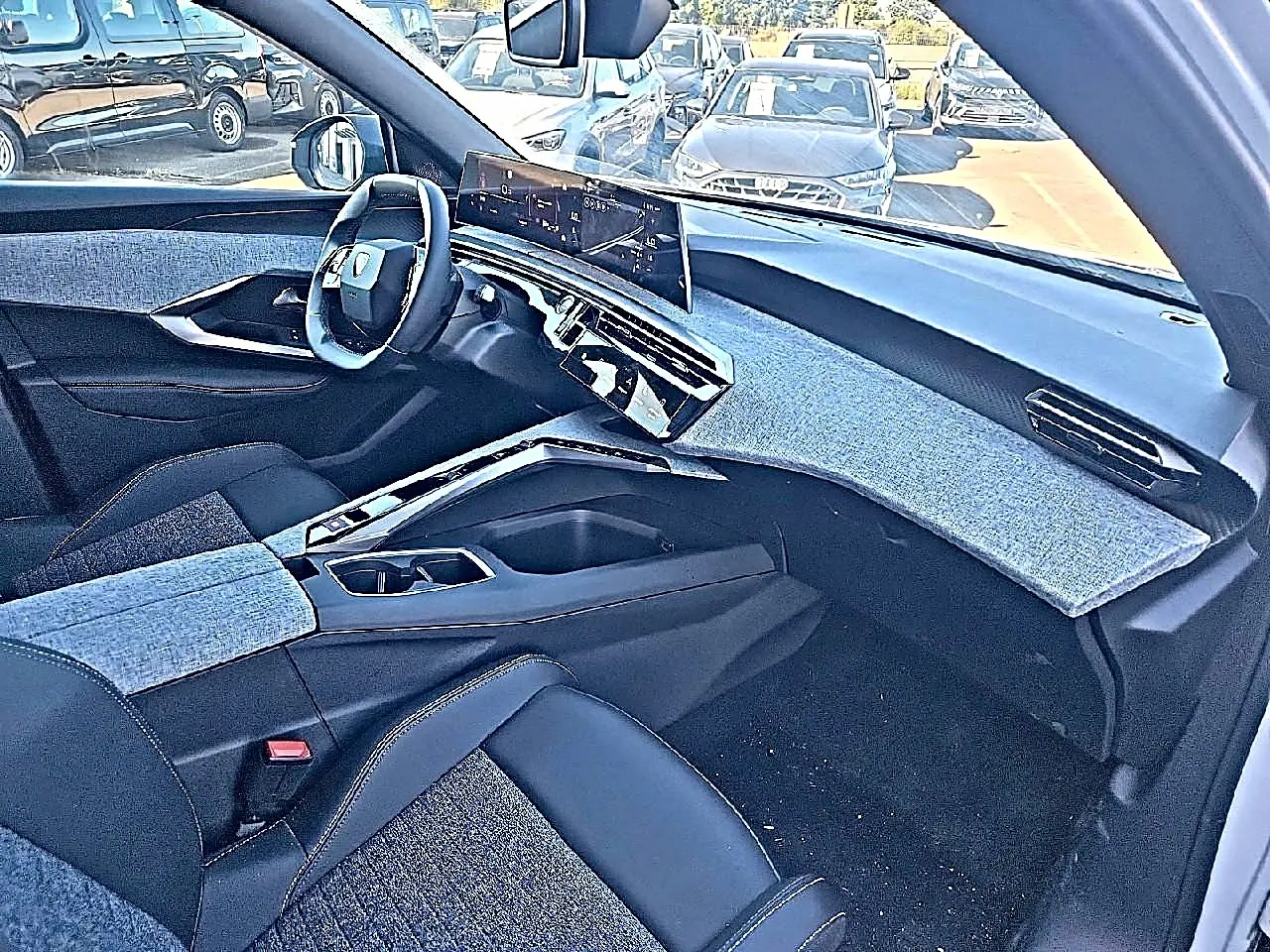 Vue intérieure côté passager du Peugeot 5008 Hybrid 145 allure e-dcs6 2025, tableau de bord et sièges en tissu bleu et cuir noir.