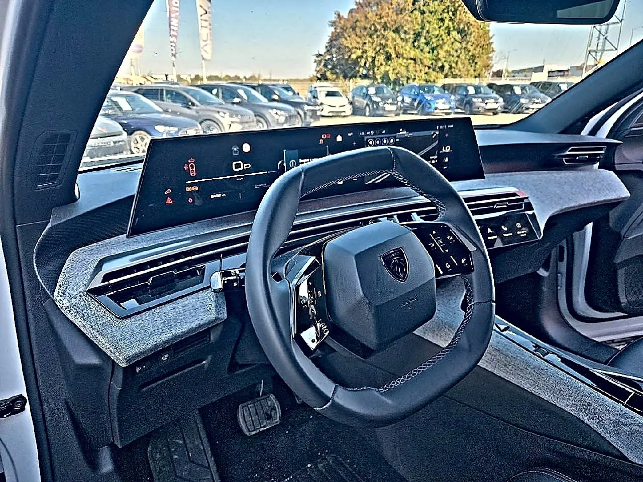 Vue intérieure côté conducteur du Peugeot 5008 Hybrid blanc, avec volant compact et tableau de bord numérique large.