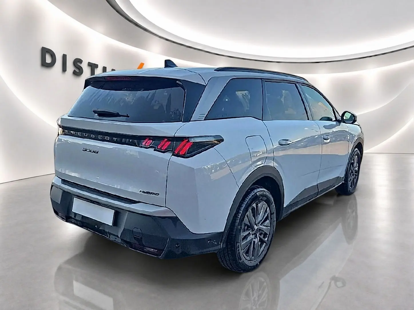 Vue 3/4 arrière droit d'un Peugeot 5008 Hybrid blanc avec feux arrière LED et vitres arrière surteintées dans un showroom.
