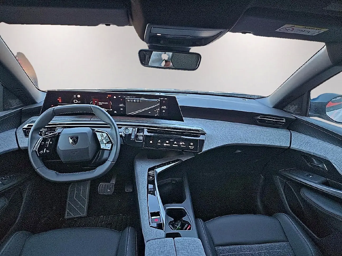 Vue intérieure avant du Peugeot 5008 Hybrid blanc, avec tableau de bord numérique et volant cuir multifonction.