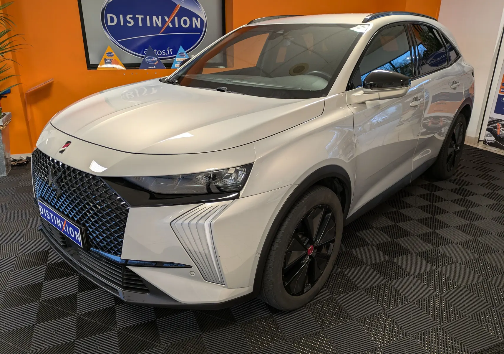 DS7 BlueHDi 130 2023 en Chrystal Pearl, vue 3/4 avant droit, avec calandre distinctive et jantes noires.