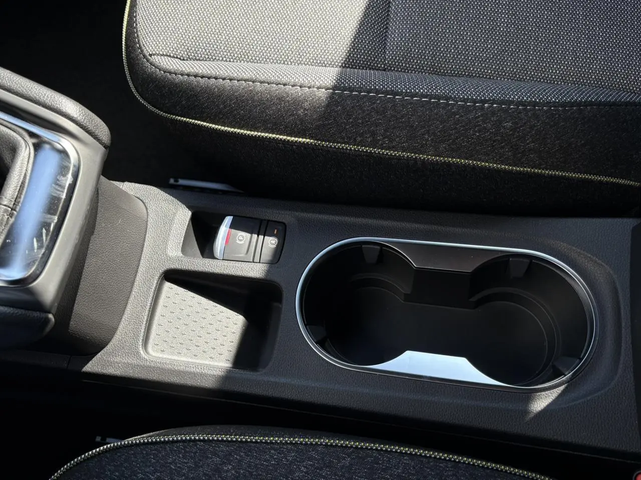 Gros plan sur la console centrale du Renault Captur 2025 avec frein de parking électrique et porte-gobelets noirs.