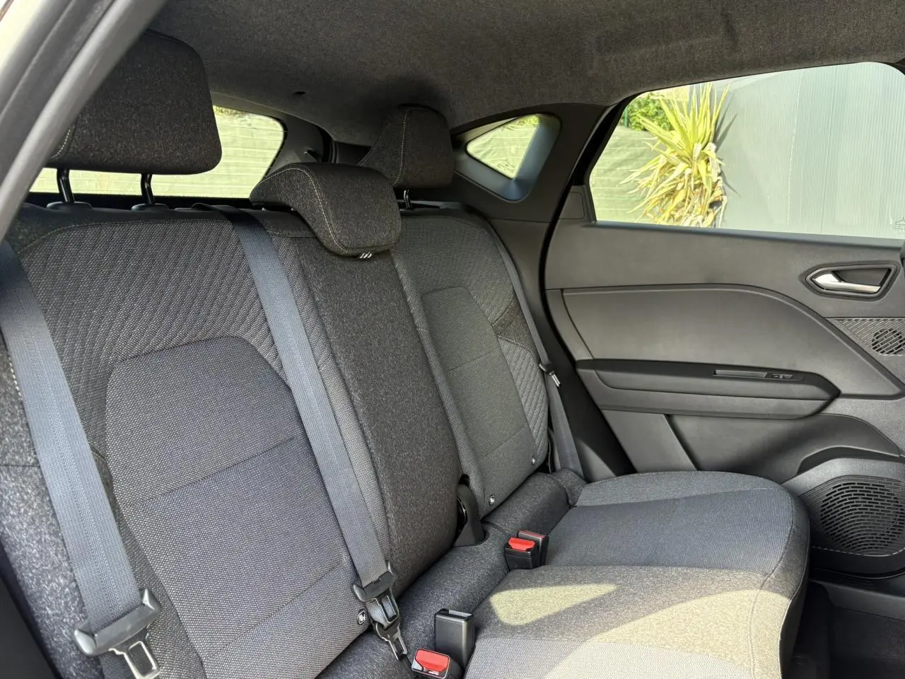 Vue intérieure côté droit de la banquette arrière grise du Renault Captur 2025 avec ceintures et appuis-tête.