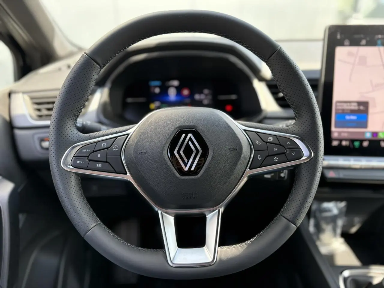 Volant en cuir perforé avec logo Renault au centre, tableau de bord numérique et écran tactile à droite du Renault Captur 2025.