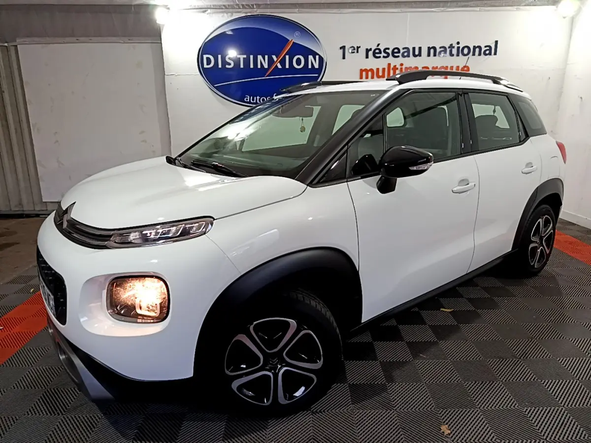Citroën C3 Aircross blanc vue 3/4 avant droit, feux avant allumés et jantes noires distinctives.