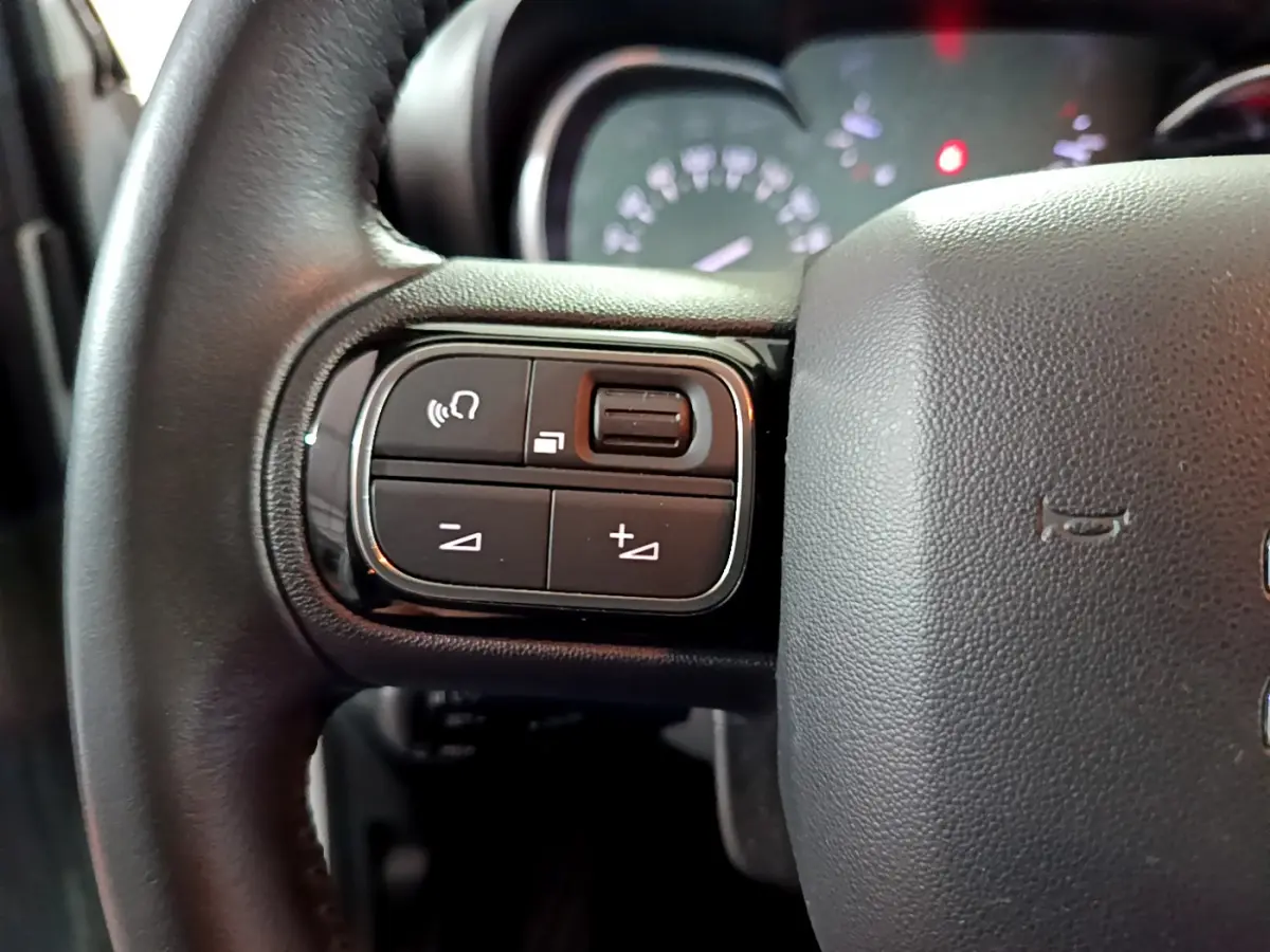 Gros plan sur les commandes gauche du volant cuir d’une Citroën C3 Aircross 2019, avec tableau de bord en arrière-plan.