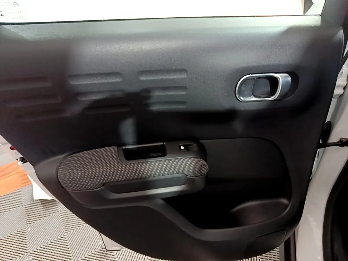 Vue rapprochée de la porte arrière droite noire du Citroën C3 Aircross blanc, avec poignée intérieure argentée.