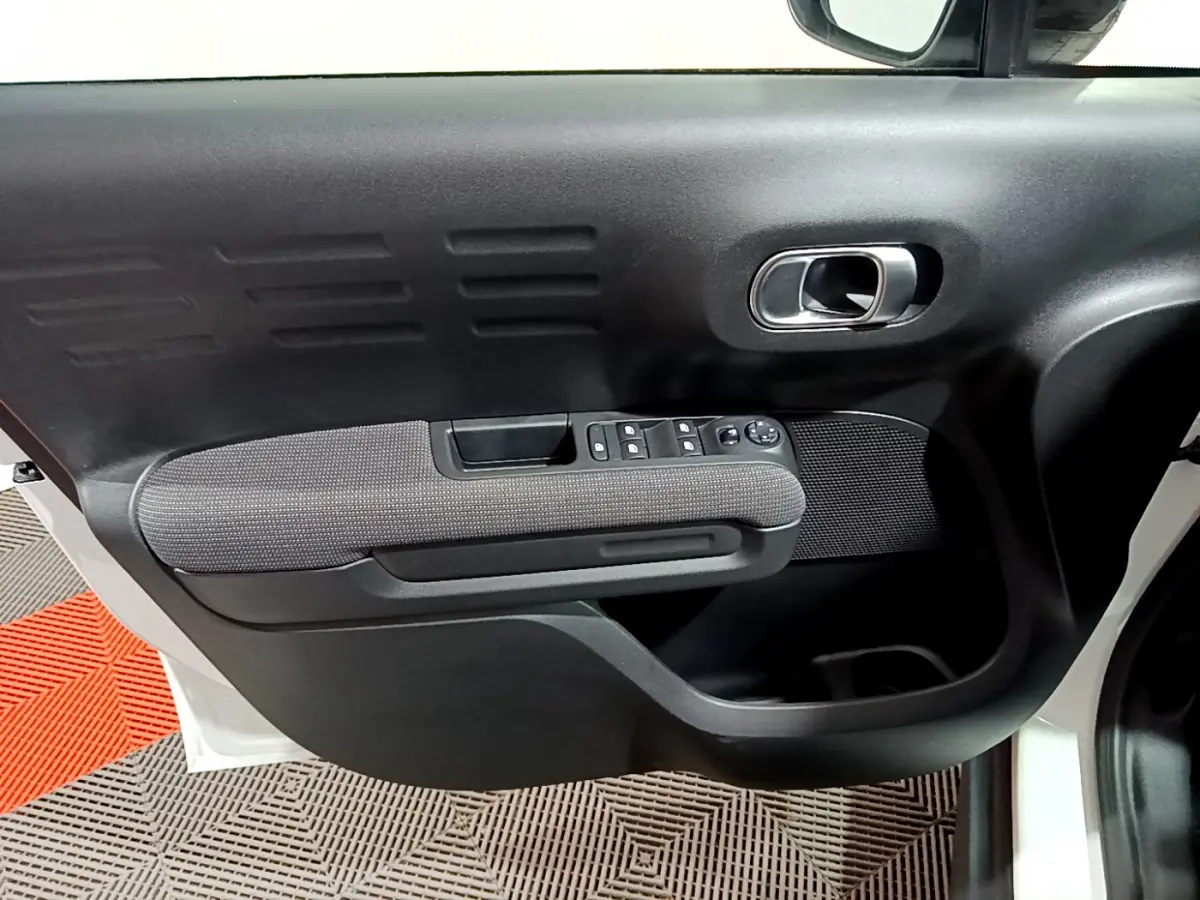 Gros plan sur la porte avant gauche noire et grise du Citroën C3 Aircross blanc, avec commandes électriques des vitres.